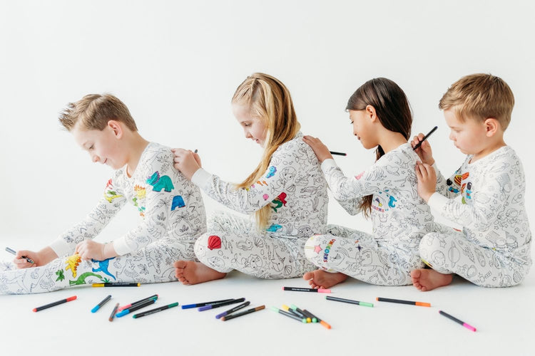 Kids wearing coloring pajamas and coloring each other enjoying a screen-free activity