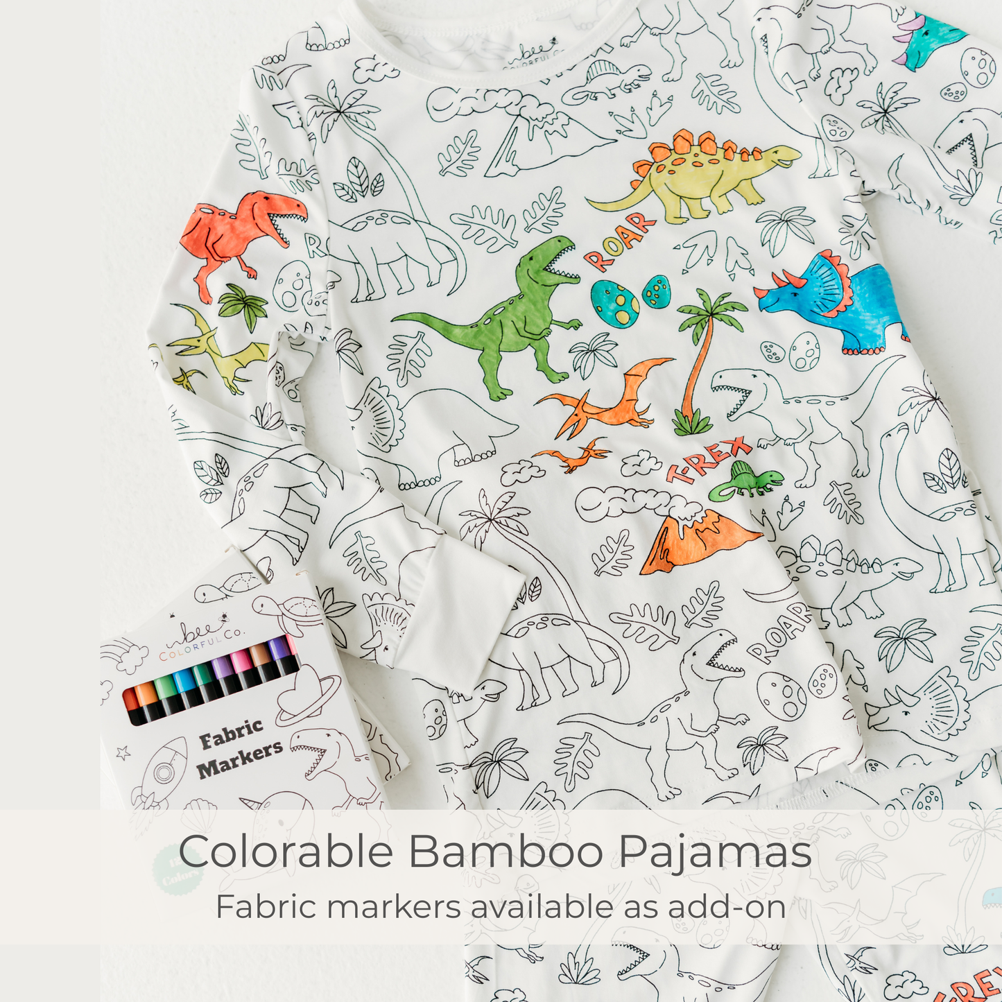 Colorable bamboo pajamas with dinosaur patterns and fabric markers on a white background